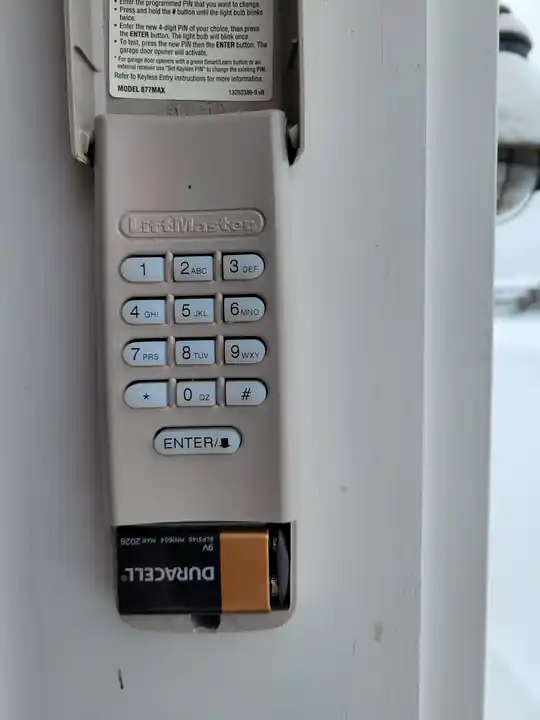 Open LiftMaster keypad on a Vermont garage, showing the battery compartment