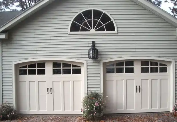 Two cream carriage doors with arched window rows under a fan-light gable