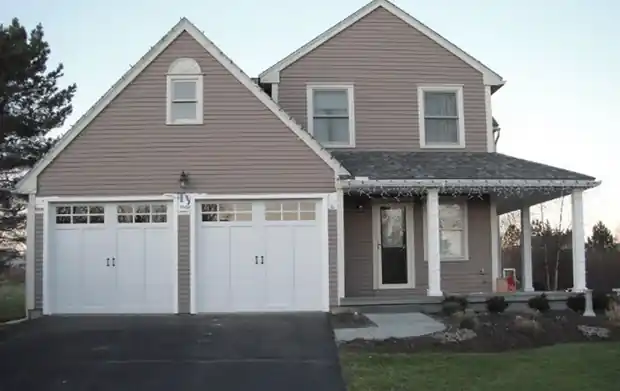 Two white carriage doors on a taupe house, wide view