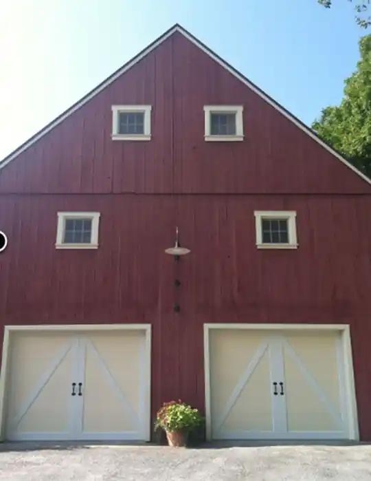Red barn-style building with two cream X-brace garage doors installed by Limoge & Sons