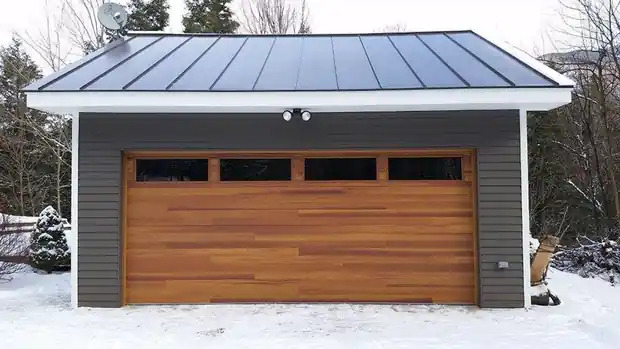 Modern flat-roof garage with a long horizontal dark door in the snow