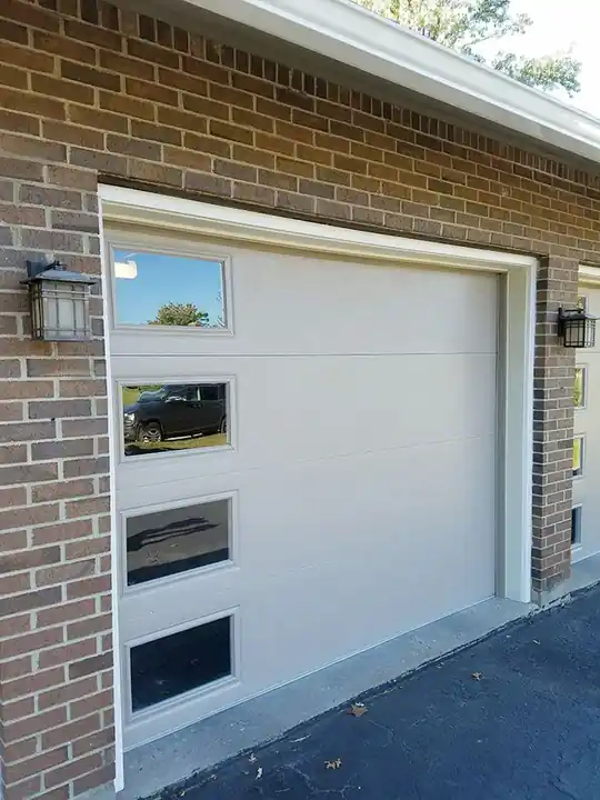 Tall cream flush door with a vertical strip of windows against a brick wall