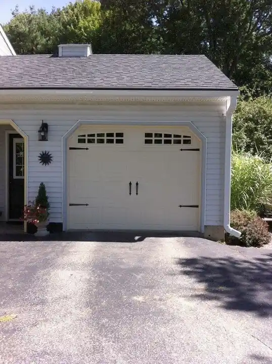 Single cream carriage door with black hardware on a small gabled garage