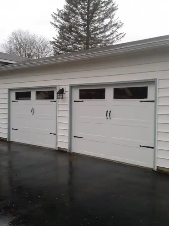 Two white long-panel doors with windows on grey clapboard