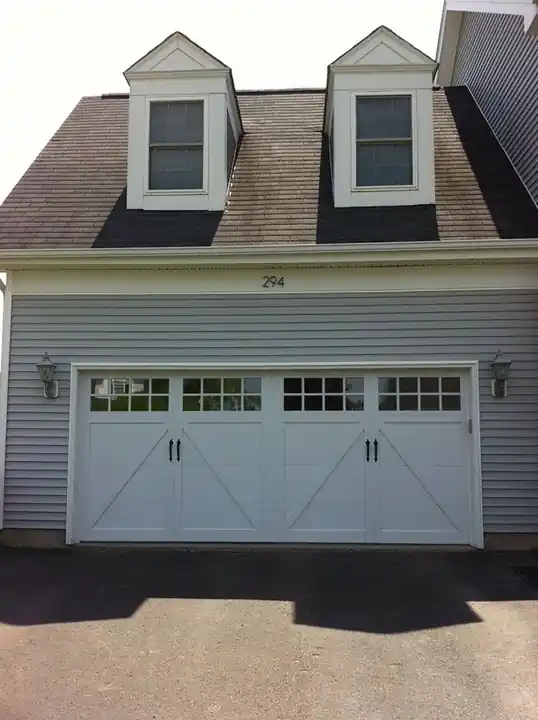 White carriage door with X-brace under twin dormers
