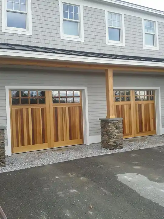 Two dark doors with glass tops beside a stone column on an upper-storey garage