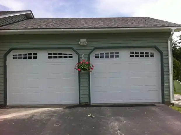 Two white windowed doors on a green house with cut corner trim