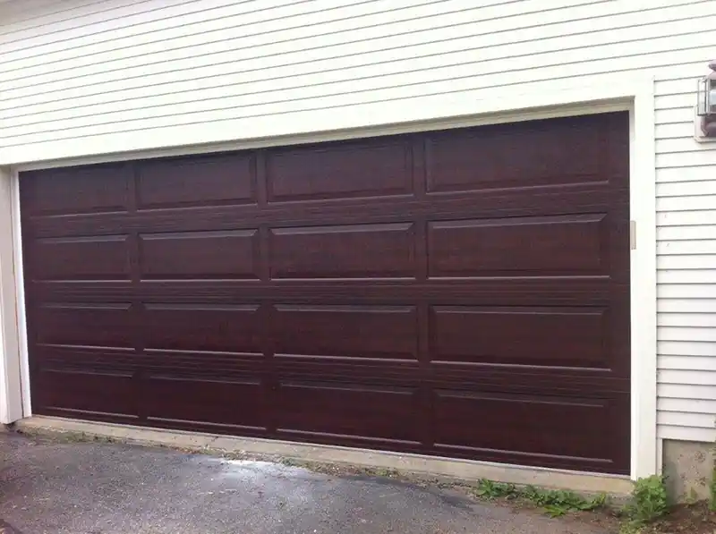 One very wide dark long-panel door on white siding