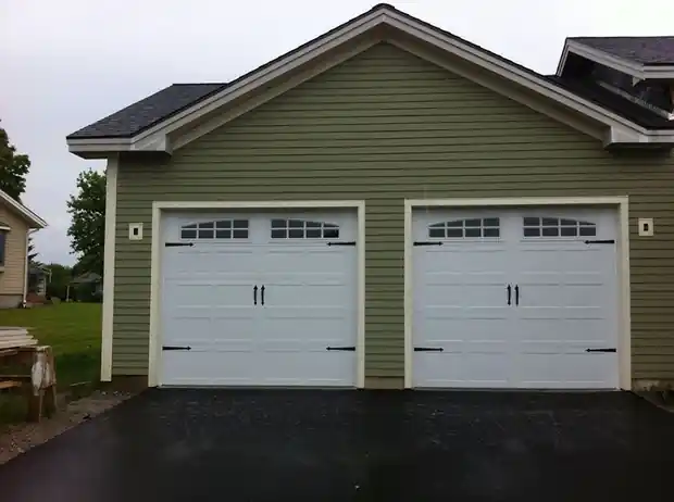 Two white windowed doors on a green house with a gravel drive