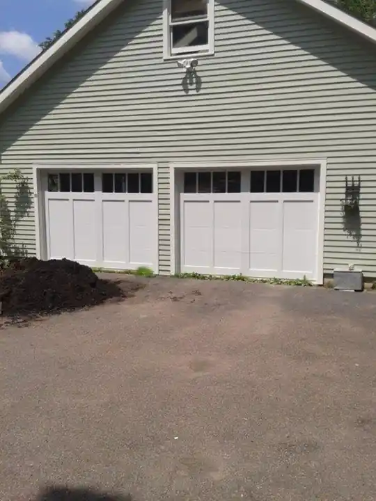 Two cream windowed doors on grey siding with a mulch pile in front