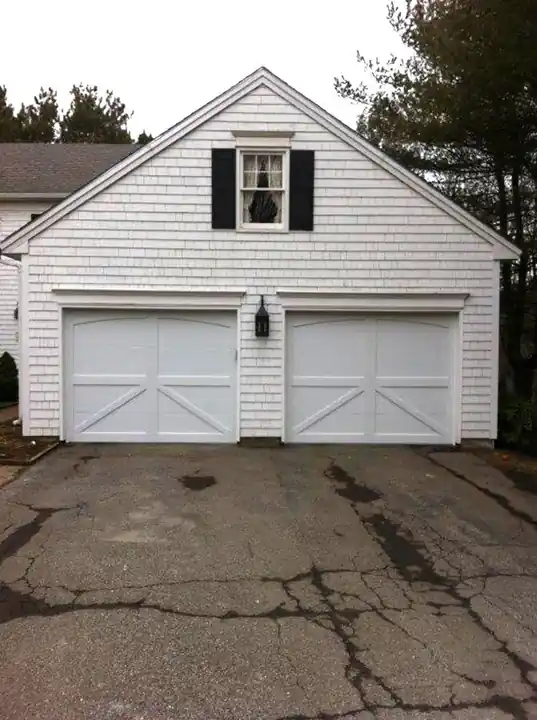 White shingled two-car garage with two white X-brace doors