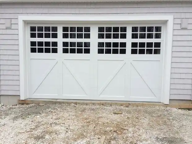 Close view of one wide white X-brace door with grid windows