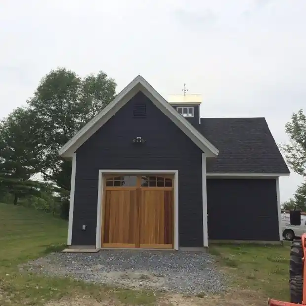 Navy carriage house with a single dark door and a grass approach